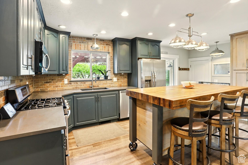 Kitchen with wooden counters, a sink, appliances with stainless steel finishes, decorative backsplash, and recessed lighting