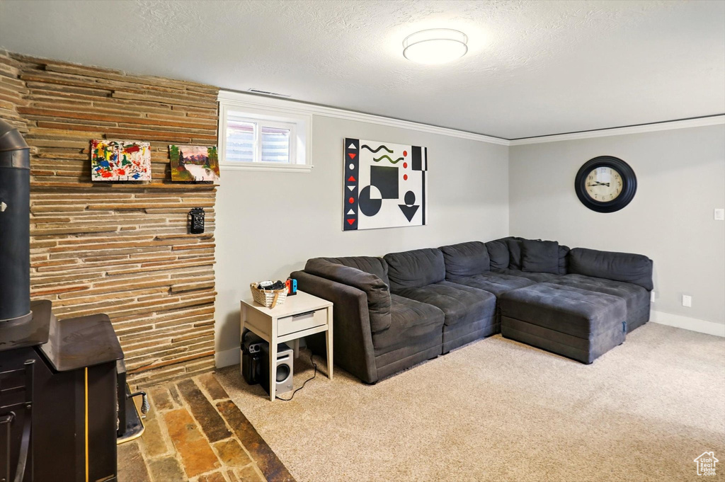 Living room featuring a wood stove, a textured ceiling, baseboards, and ornamental molding