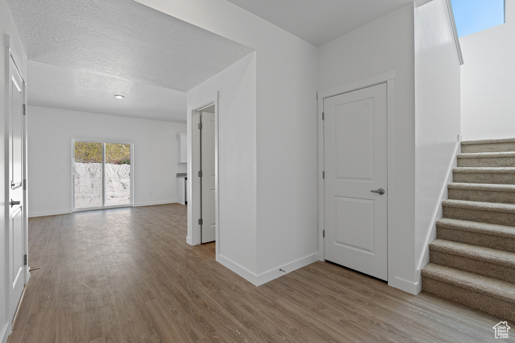 Interior space with stairway, a textured ceiling, baseboards, and wood finished floors