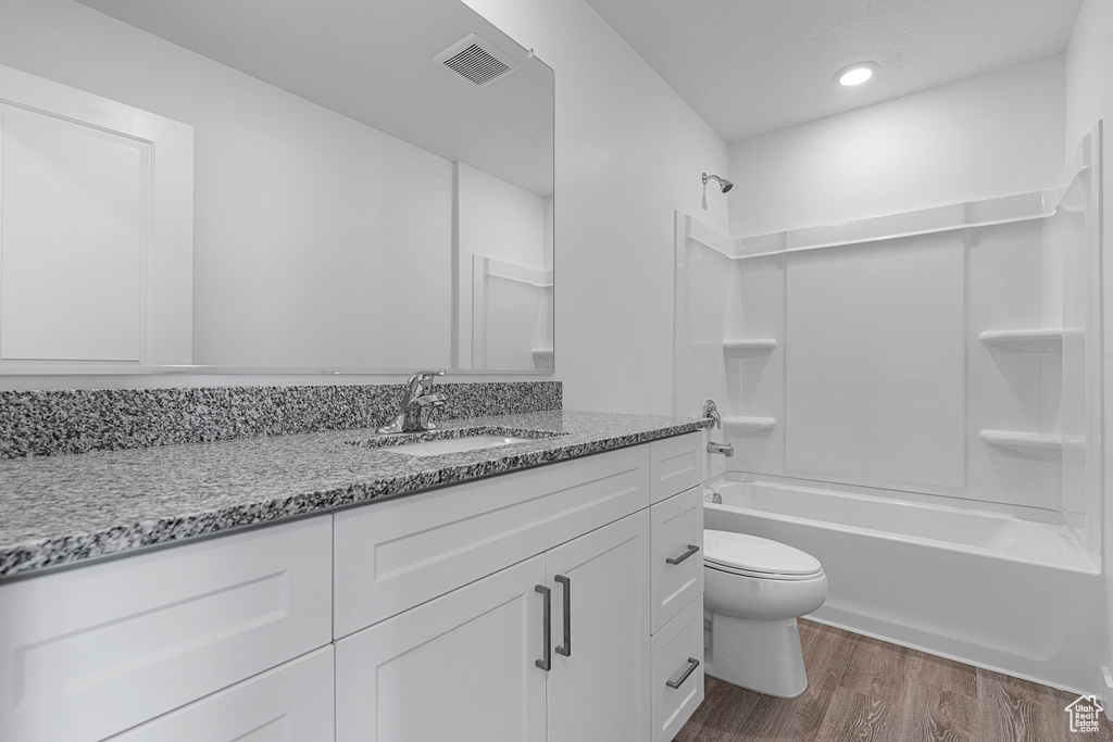 Full bathroom with toilet, tub / shower combination, wood finished floors, visible vents, and vanity