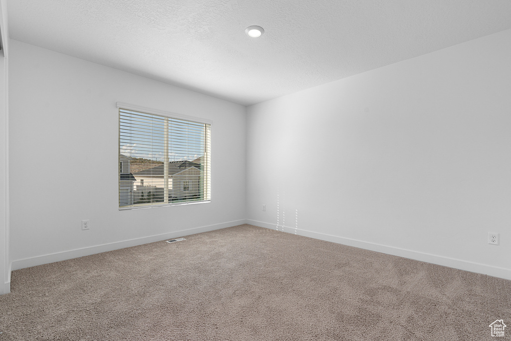 Carpeted empty room with baseboards and visible vents