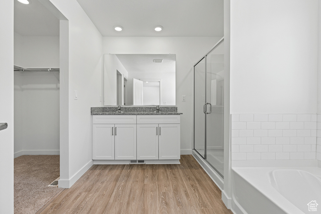 Bathroom featuring a stall shower, a spacious closet, a sink, and wood finished floors