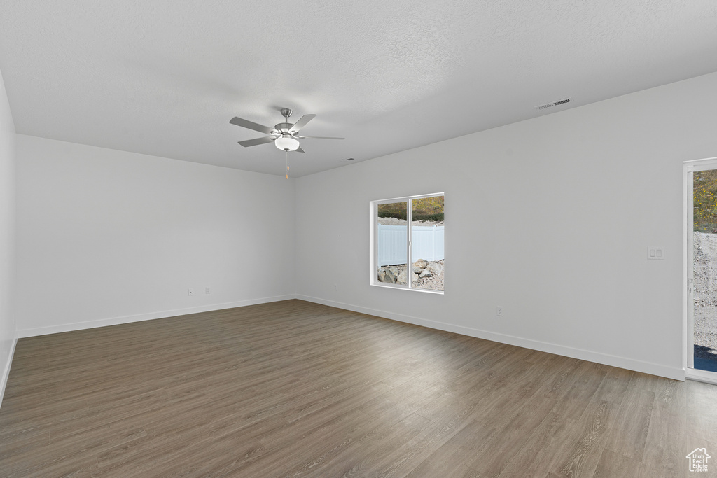Unfurnished room with baseboards, visible vents, wood finished floors, and a ceiling fan