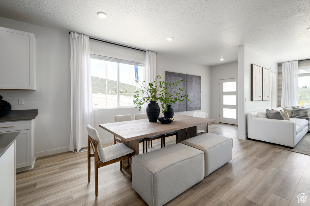 Dining space with recessed lighting, light wood-style floors, baseboards, and a textured ceiling