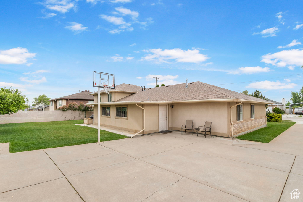 Rear view of house featuring a lawn, a patio area, stucco siding, and roof with shingles