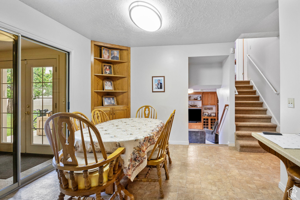 Dining room featuring stairway, a textured ceiling, and baseboards