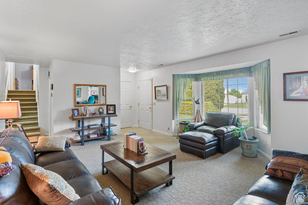 Living area featuring baseboards, carpet flooring, visible vents, and stairway