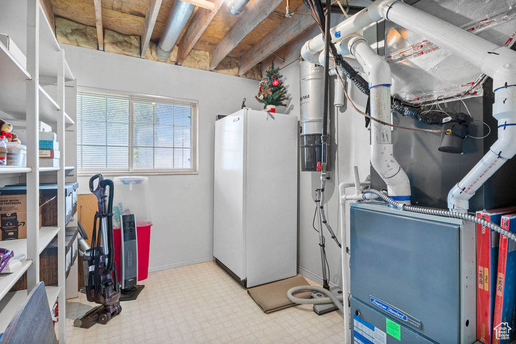 Below grade area featuring freestanding refrigerator, tile patterned floors, and heating unit