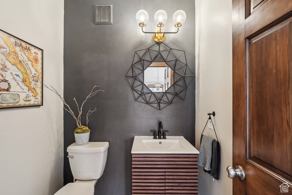 Bathroom featuring toilet, vanity, and visible vents