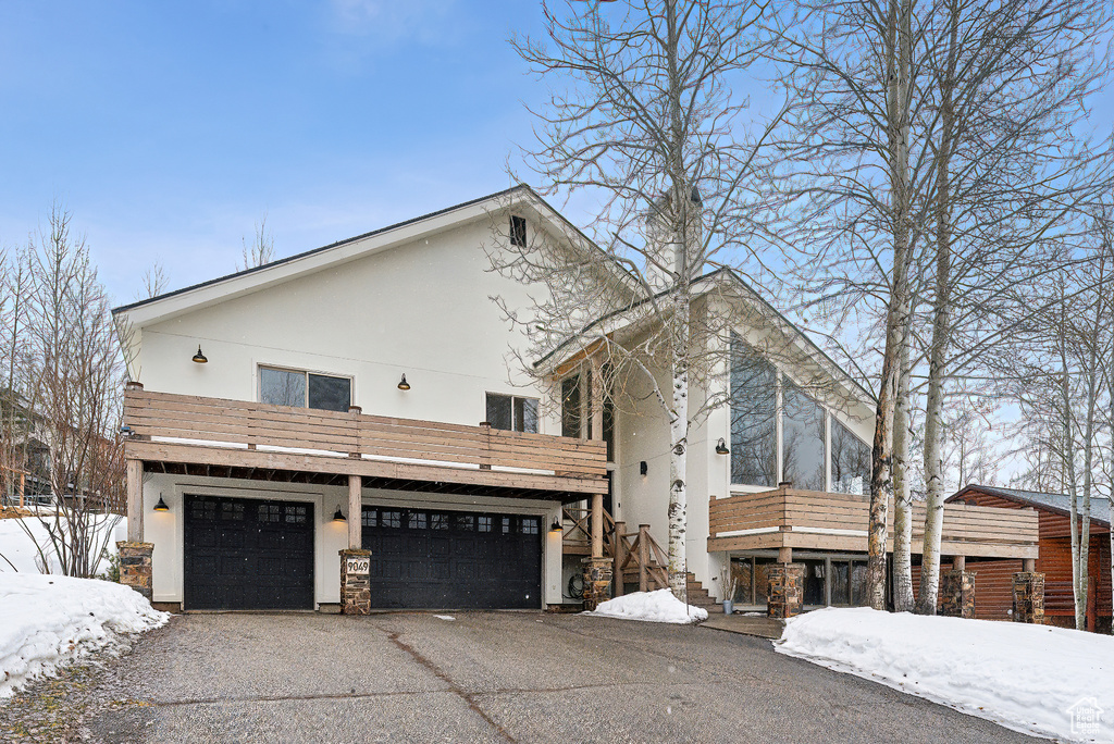 Exterior space with stairway, a garage, stucco siding, and driveway