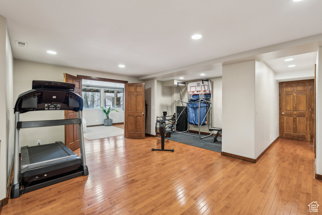 Workout room with light wood finished floors, baseboards, visible vents, and recessed lighting