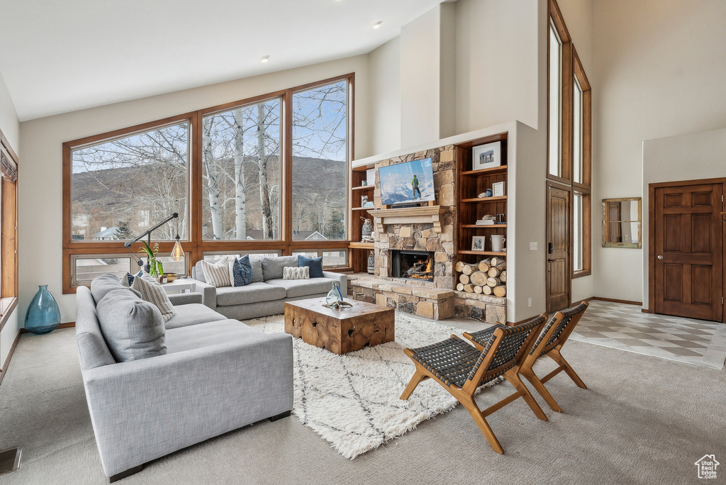 Living area featuring carpet flooring, a fireplace, visible vents, and a high ceiling