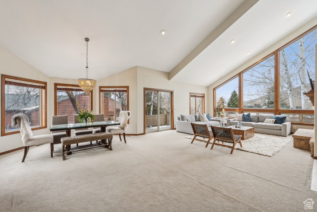 Dining room featuring light colored carpet, a wealth of natural light, baseboards, and a notable chandelier