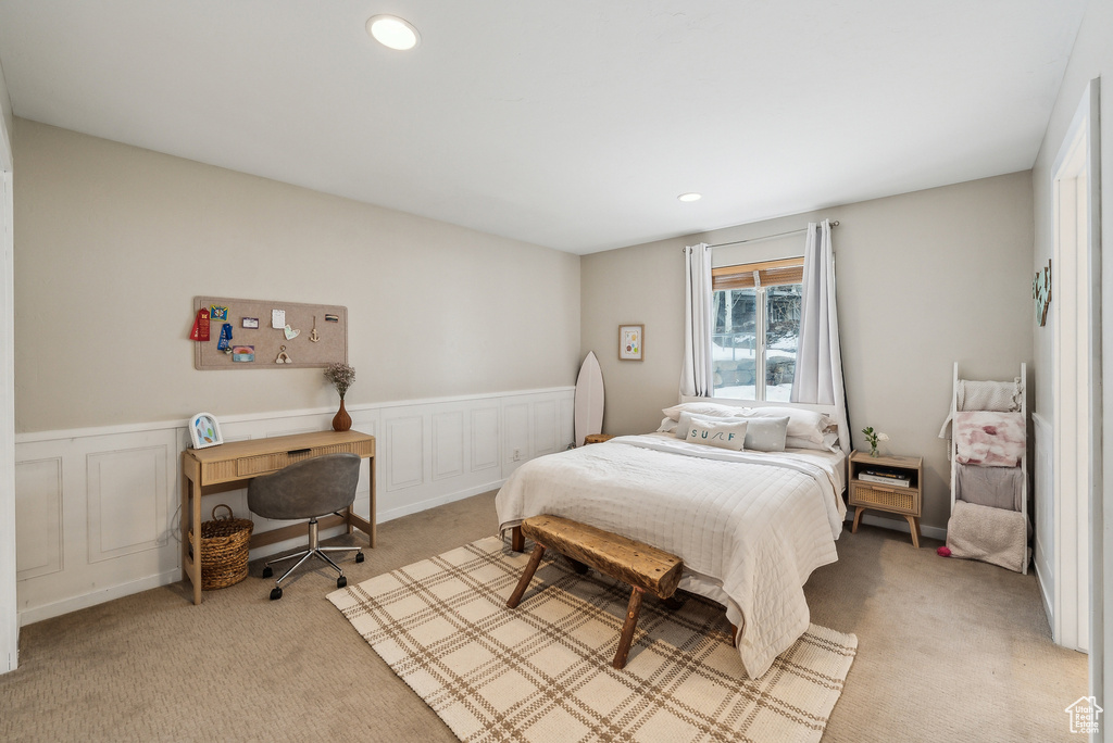 Bedroom featuring a decorative wall, wainscoting, recessed lighting, and light colored carpet