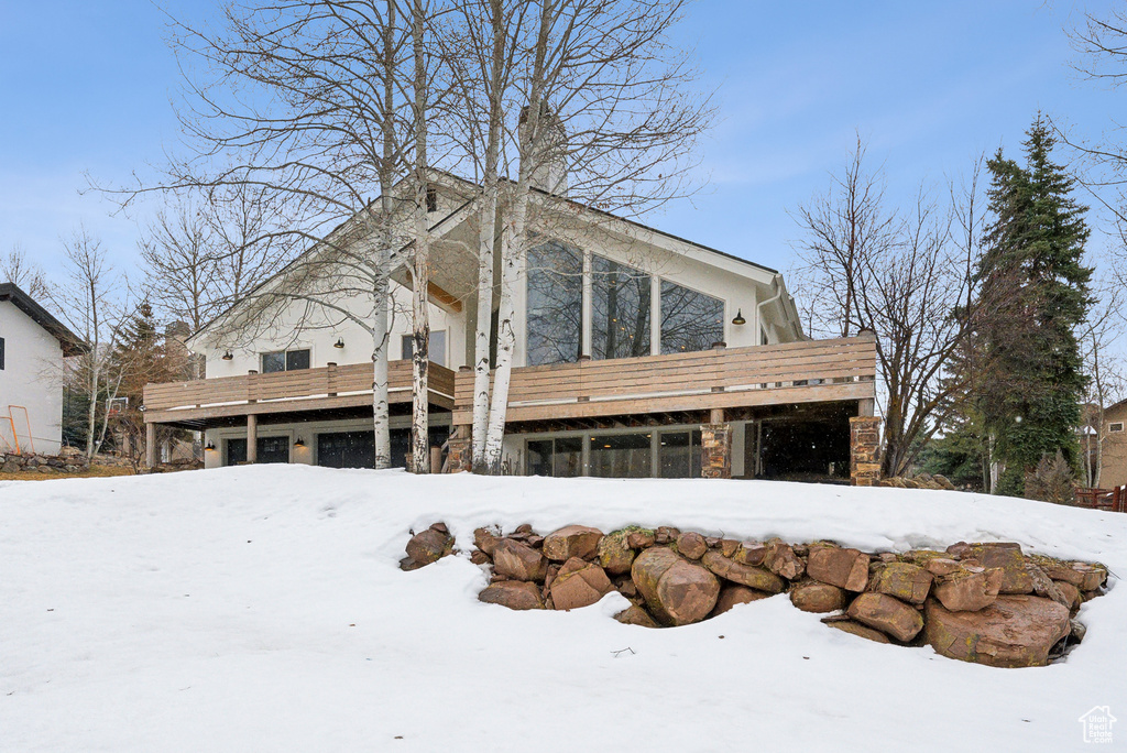 Snow covered property with stone siding