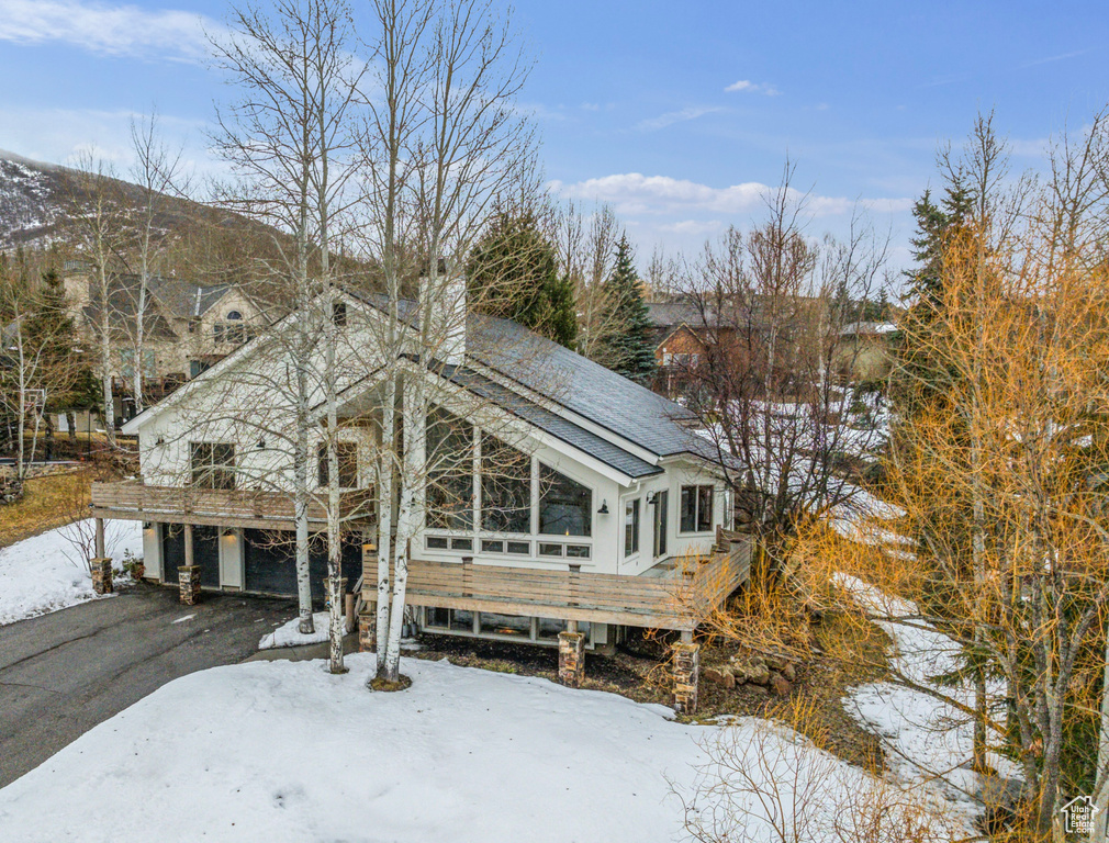 View of front facade with a chimney, driveway, a deck, and a garage