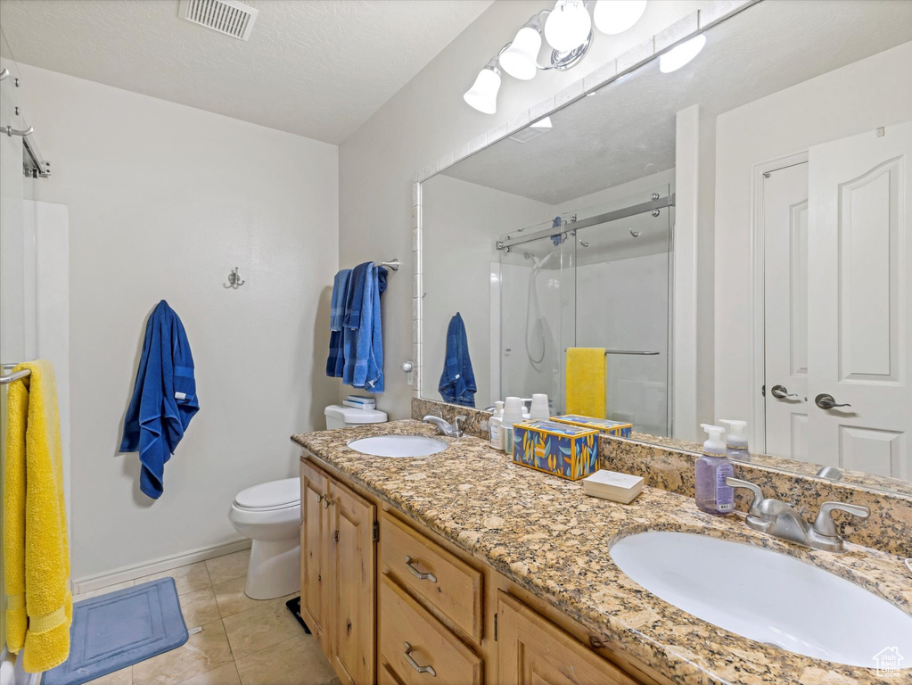 Bathroom with toilet, visible vents, a sink, and a stall shower