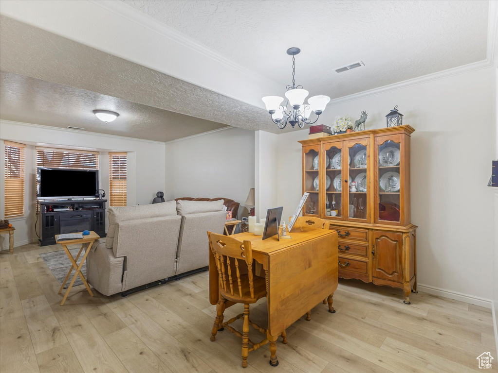Dining space with an inviting chandelier, a textured ceiling, visible vents, and light wood-style floors