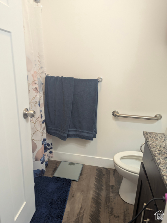 Full bathroom featuring baseboards, toilet, wood finished floors, vanity, and a shower with shower curtain