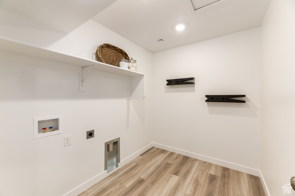 Washroom with light wood finished floors, laundry area, hookup for an electric dryer, hookup for a washing machine, and baseboards