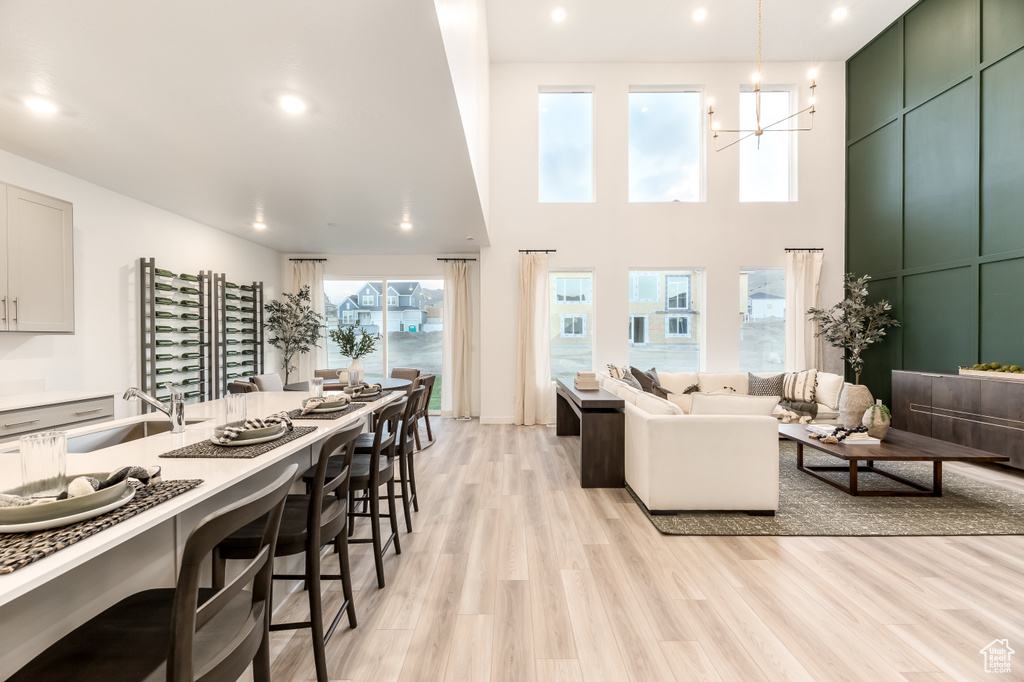 Living area featuring light wood finished floors, recessed lighting, a high ceiling, and a notable chandelier