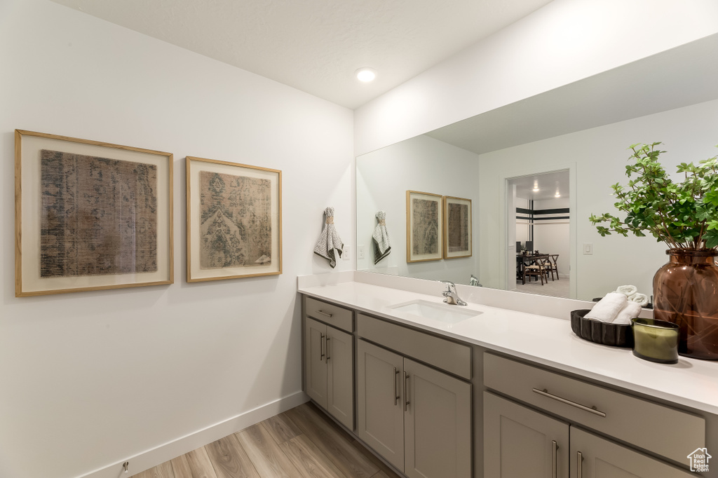 Bathroom featuring baseboards, wood finished floors, vanity, and recessed lighting