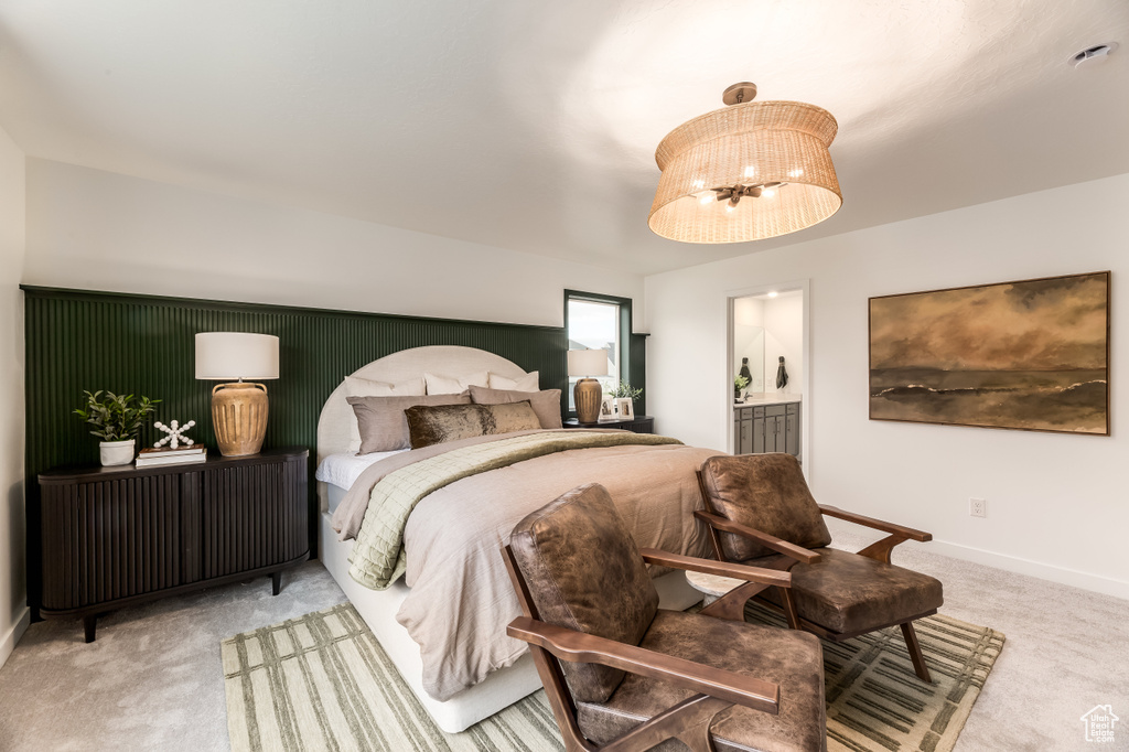 Carpeted bedroom featuring ensuite bathroom and baseboards