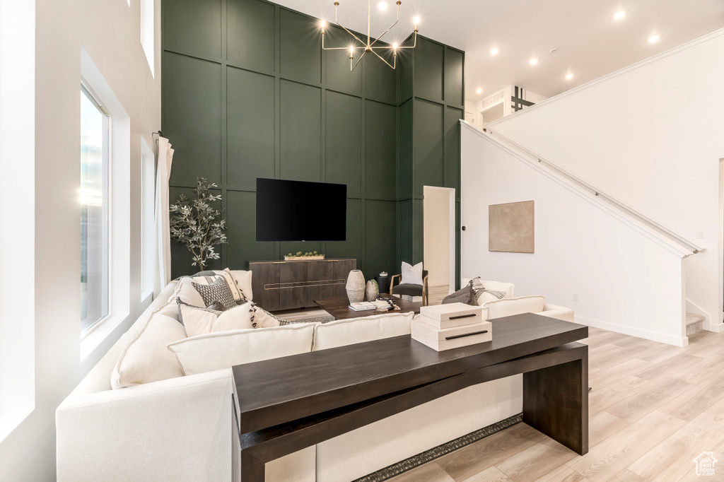 Living area featuring recessed lighting, light wood-type flooring, a towering ceiling, and stairs