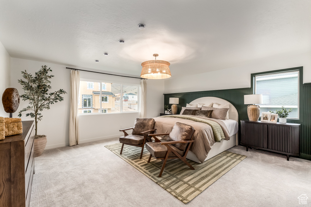Bedroom with multiple windows, light carpet, and a chandelier