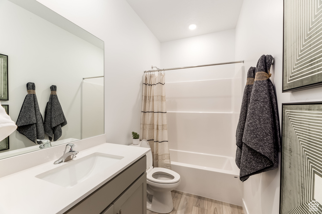 Full bathroom with vanity, toilet, shower / bath combo, and wood finished floors