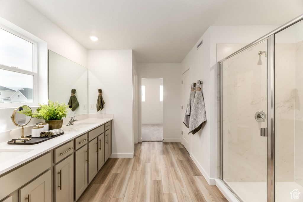 Full bathroom with a stall shower, visible vents, a sink, double vanity, and wood finished floors