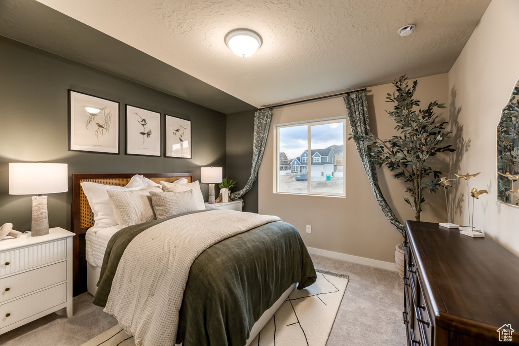 Bedroom featuring a textured ceiling, light carpet, and baseboards