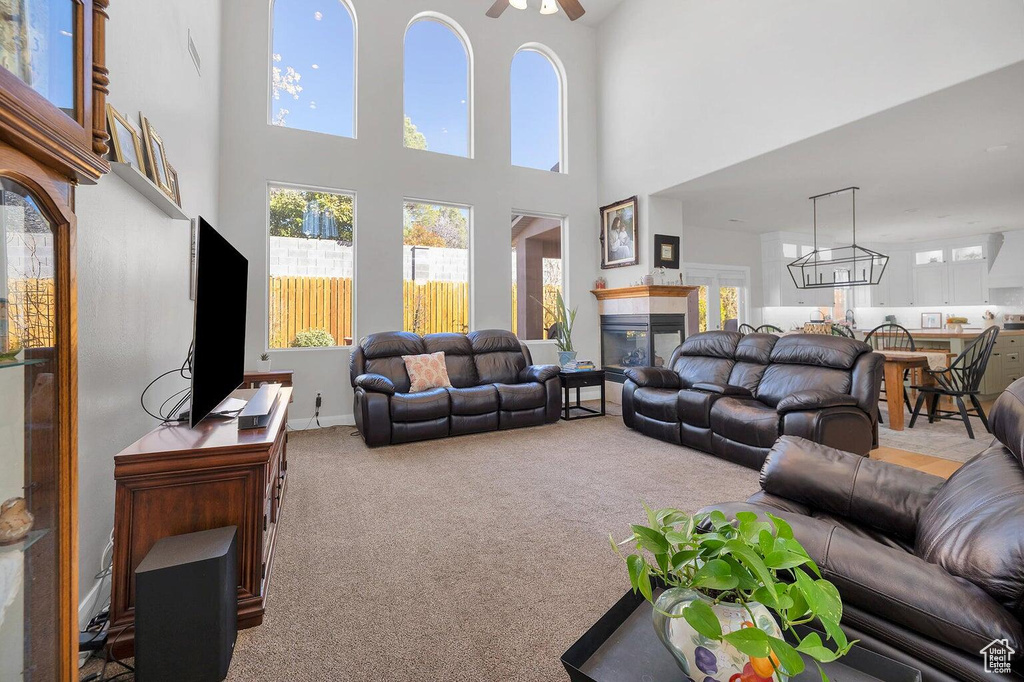 Living room with carpet flooring, plenty of natural light, a fireplace, and a towering ceiling