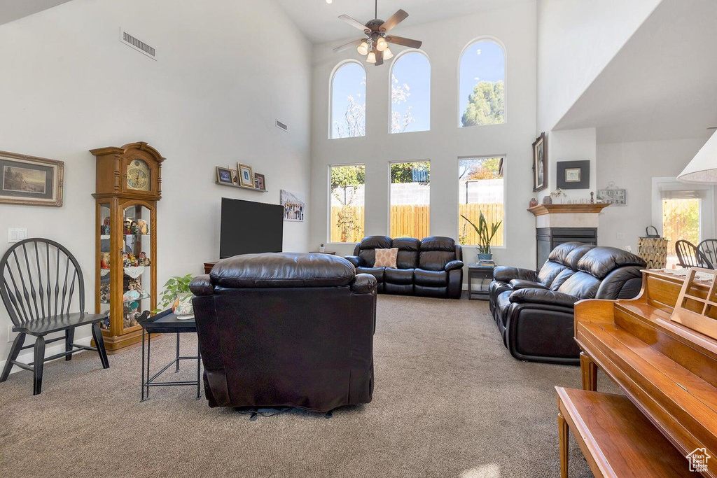 Living room featuring a towering ceiling, carpet flooring, a ceiling fan, and visible vents