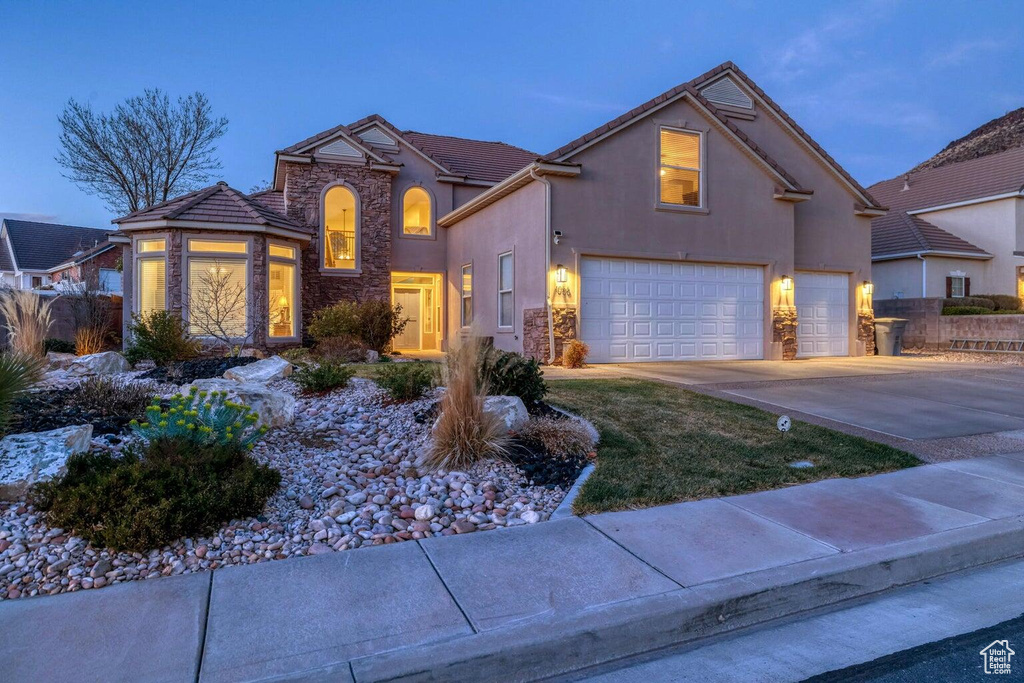 Traditional-style house featuring stone siding, stucco siding, and a garage