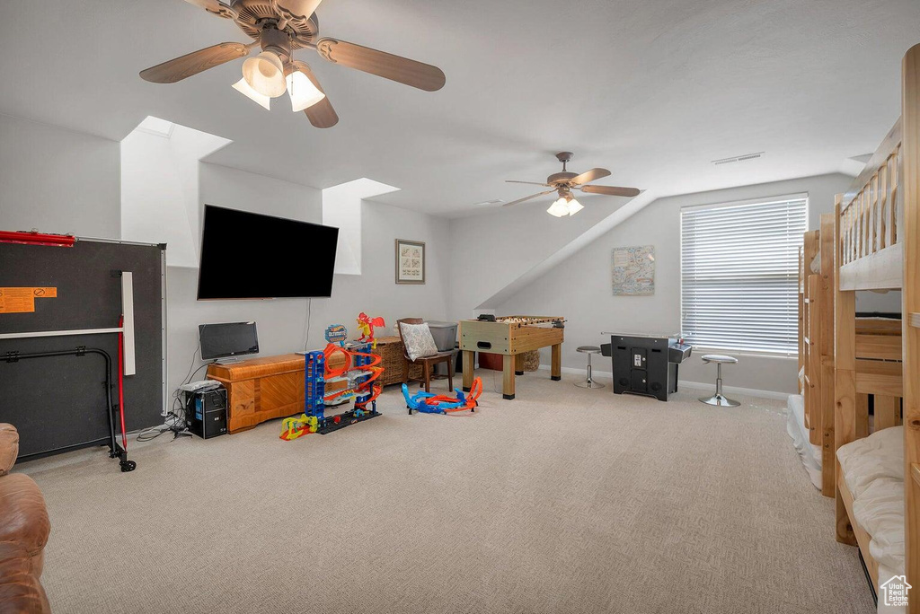 Recreation room featuring a ceiling fan, lofted ceiling, baseboards, carpet flooring, and visible vents