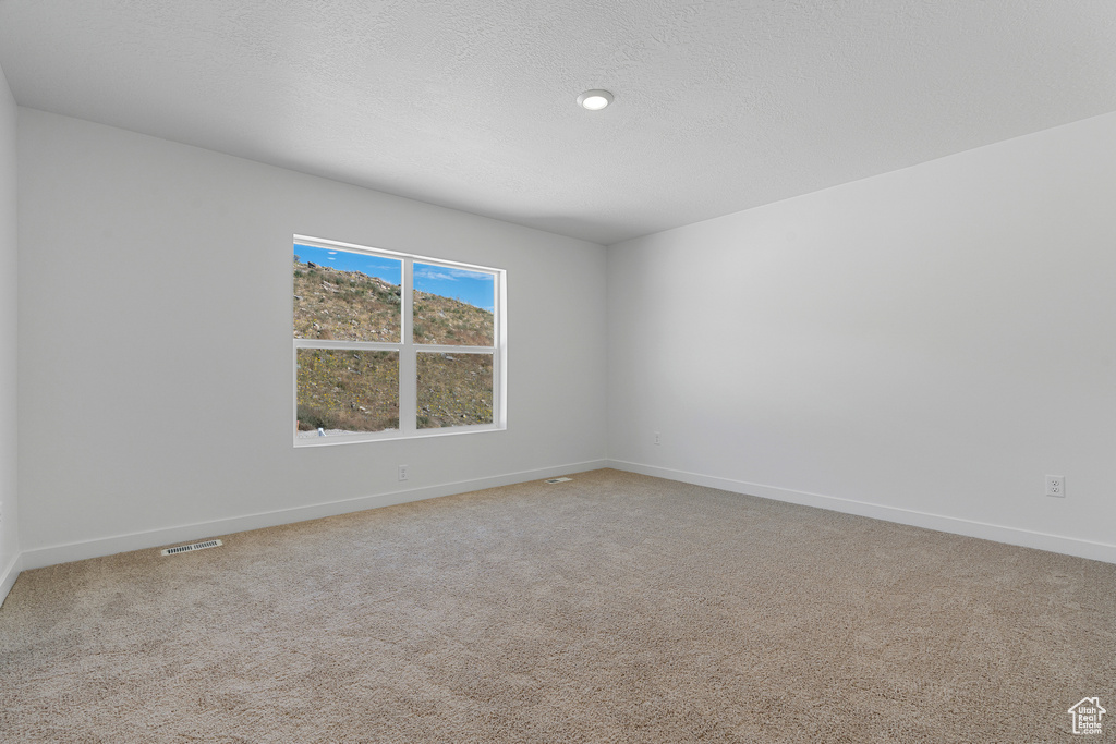 Empty room featuring light colored carpet, baseboards, and visible vents