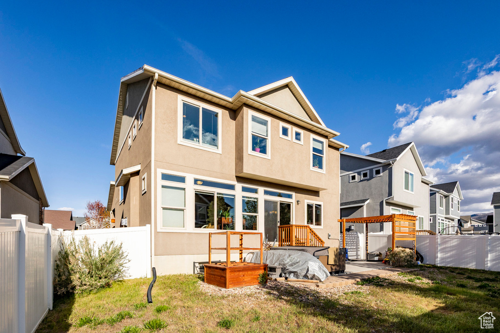 Rear view of house with a yard, stucco siding, fence, and a residential view