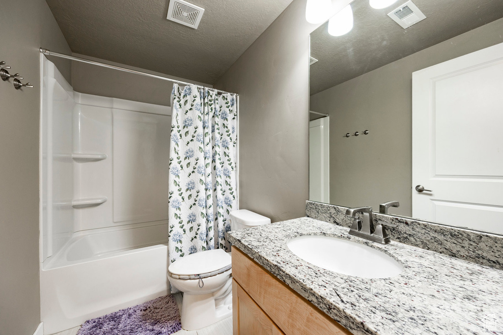Bathroom with vanity, toilet, visible vents, and shower / bath combo