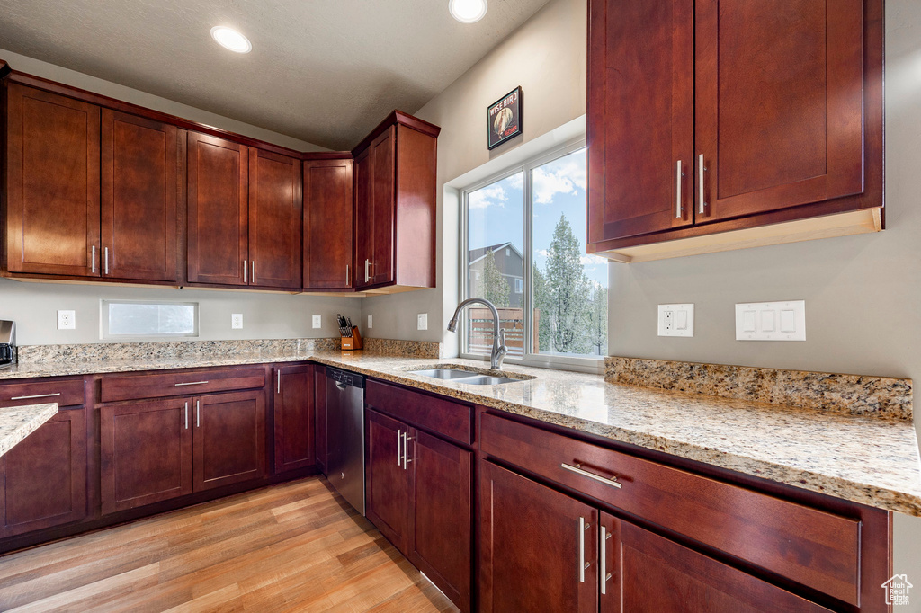 Kitchen featuring a sink, recessed lighting, light wood-style flooring, stainless steel dishwasher, and light stone countertops
