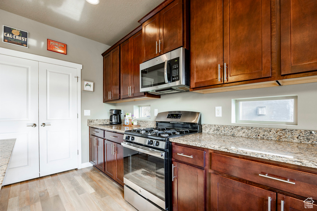 Kitchen featuring light stone counters, light wood finished floors, and appliances with stainless steel finishes