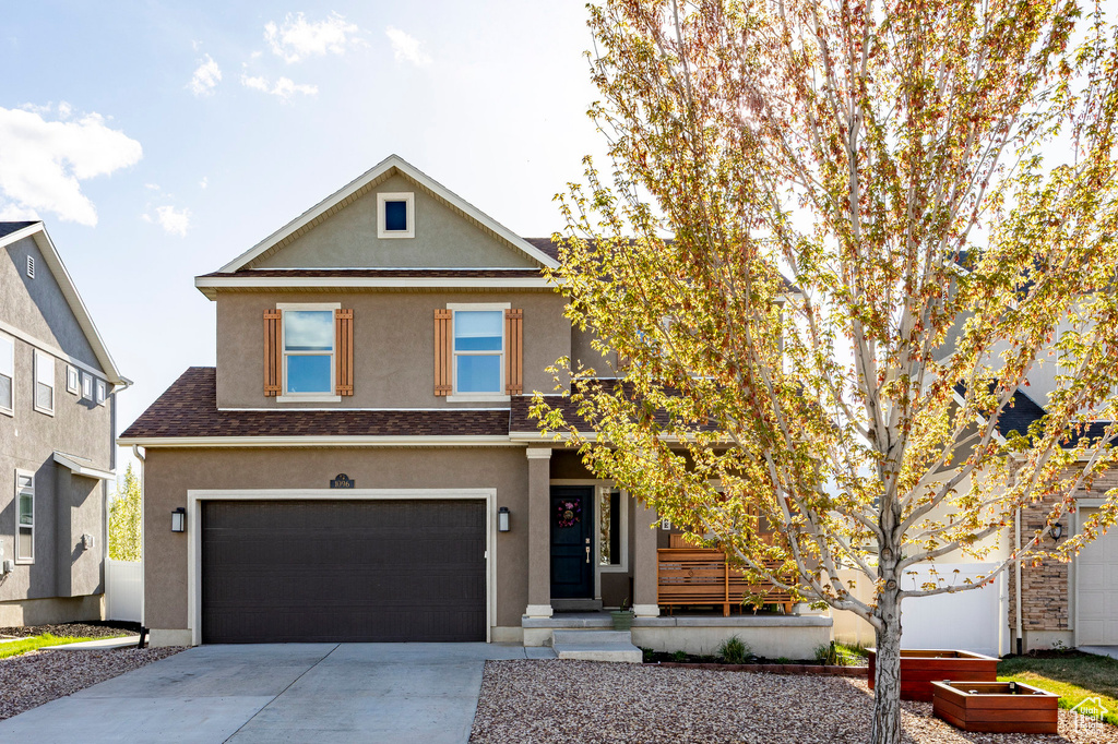 Traditional-style house featuring an attached garage, stucco siding, and driveway