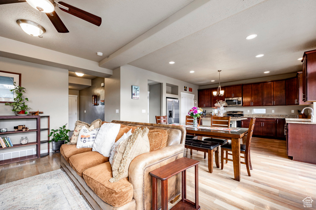 Living room with a ceiling fan, baseboards, light wood finished floors, and recessed lighting