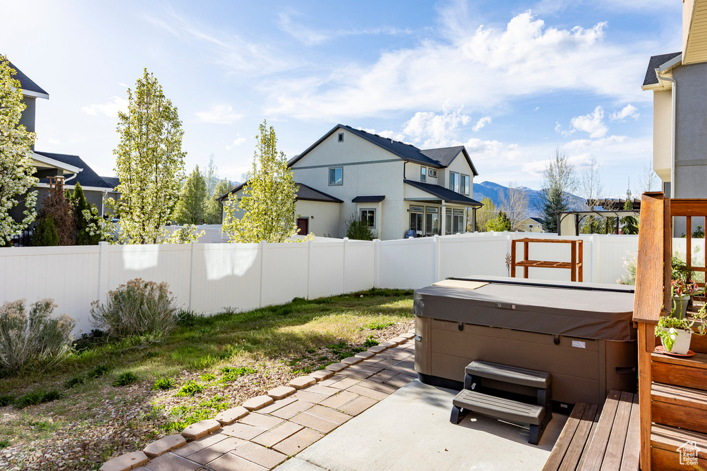 View of yard featuring a mountain view, a residential view, a hot tub, a fenced backyard, and a patio area