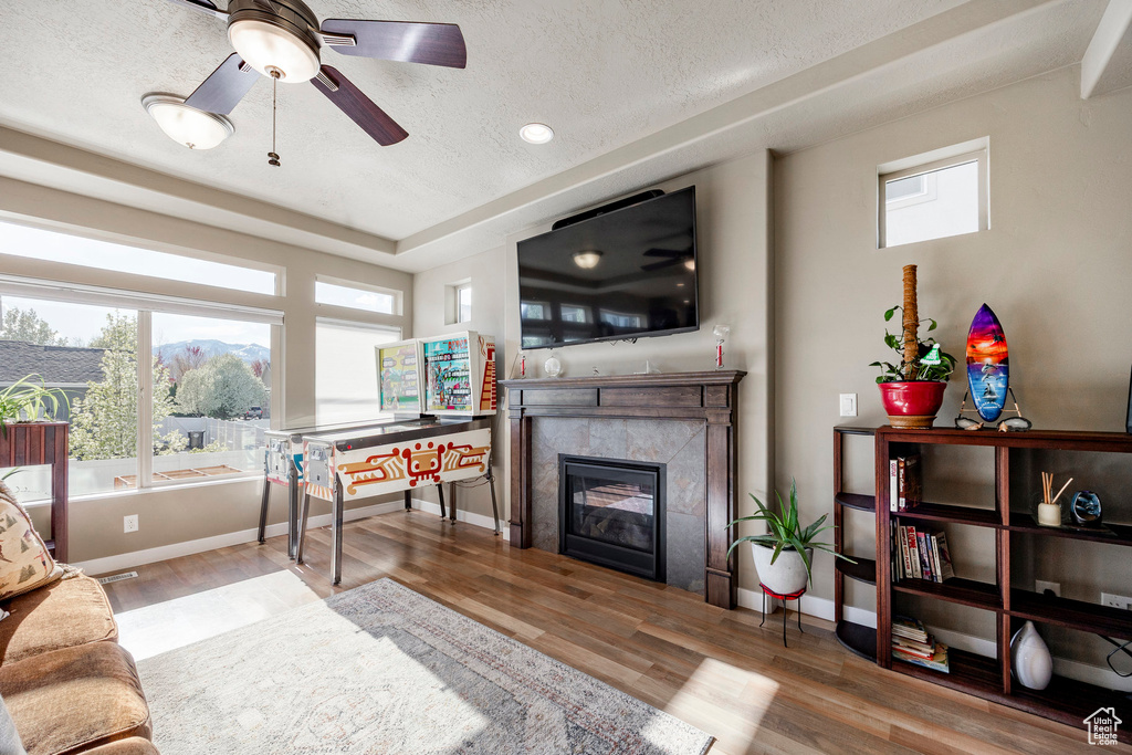 Living area with a premium fireplace, a ceiling fan, plenty of natural light, and wood finished floors