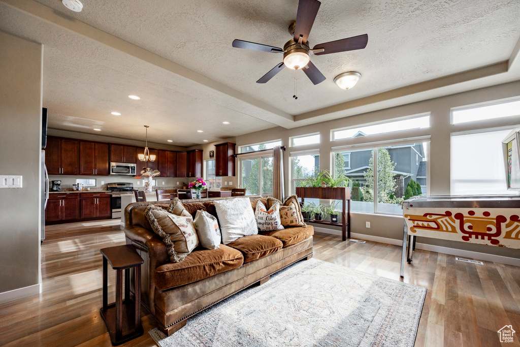 Living room with baseboards, light wood finished floors, recessed lighting, and a textured ceiling