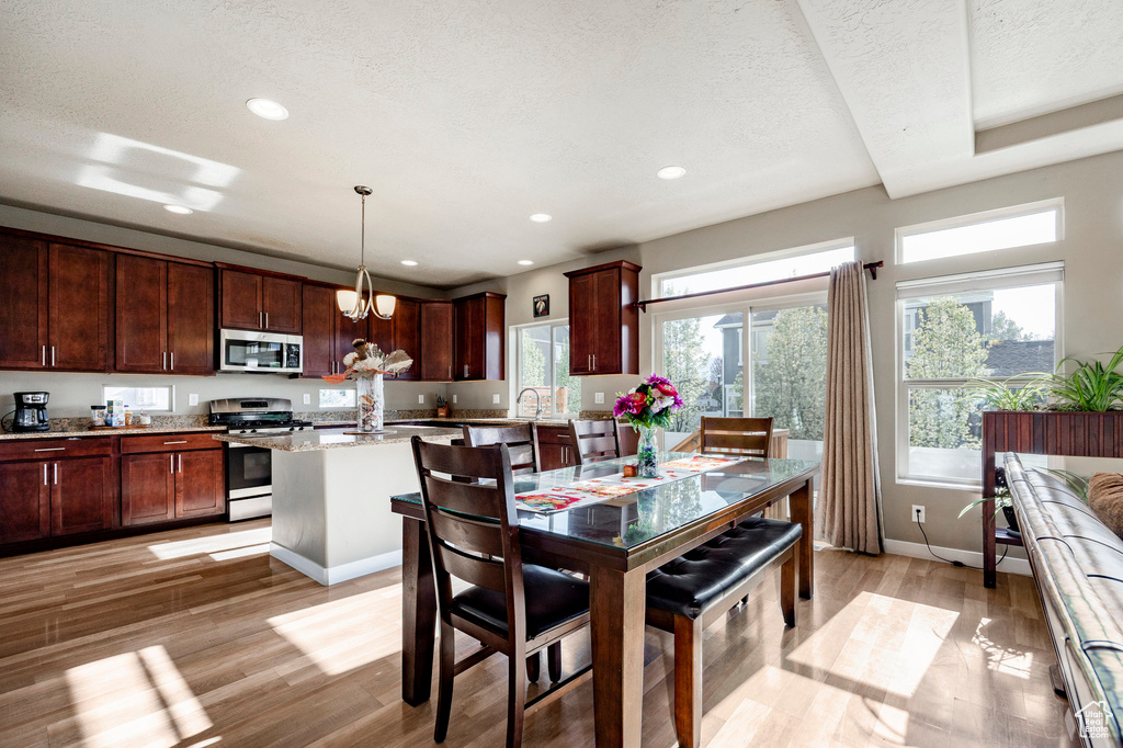 Dining space featuring light wood finished floors, an inviting chandelier, a textured ceiling, baseboards, and recessed lighting