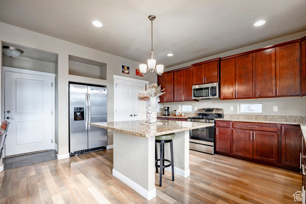 Kitchen with light wood-type flooring, a breakfast bar area, appliances with stainless steel finishes, and a kitchen island
