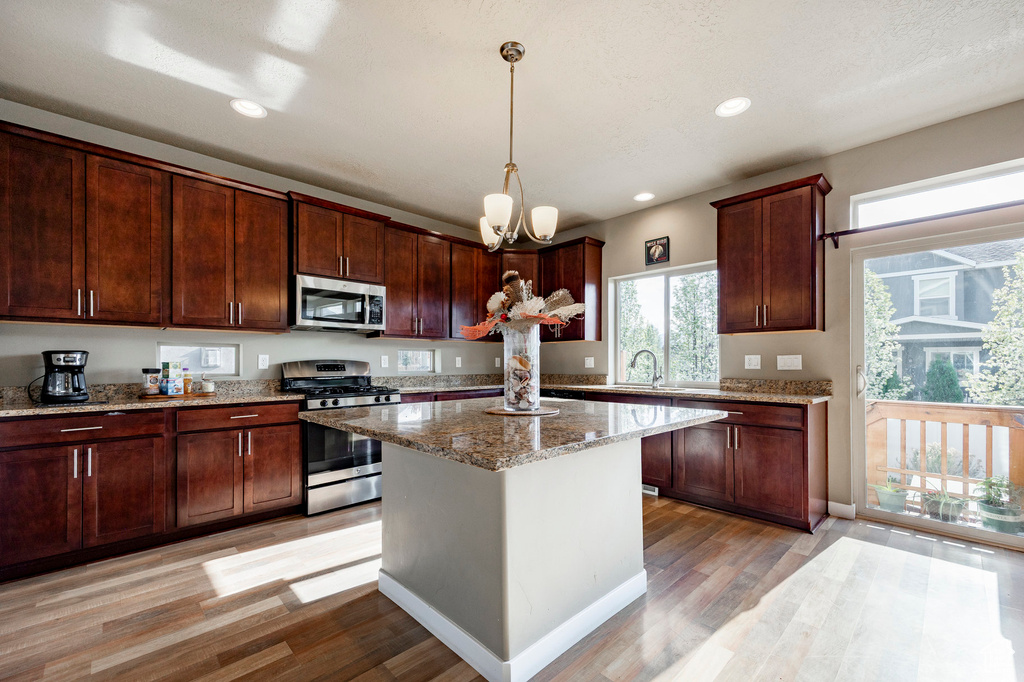 Kitchen featuring light stone countertops, recessed lighting, hanging light fixtures, light wood-style floors, and stainless steel appliances
