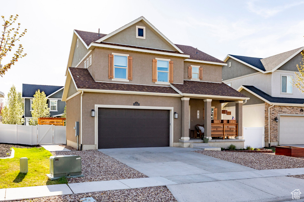 View of front facade featuring covered porch, stucco siding, a gate, and an attached garage